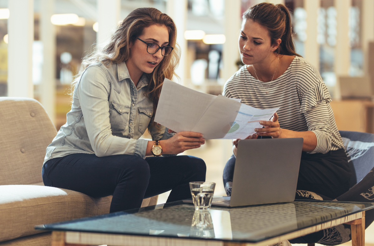 Two women looking at a spreadsheet.