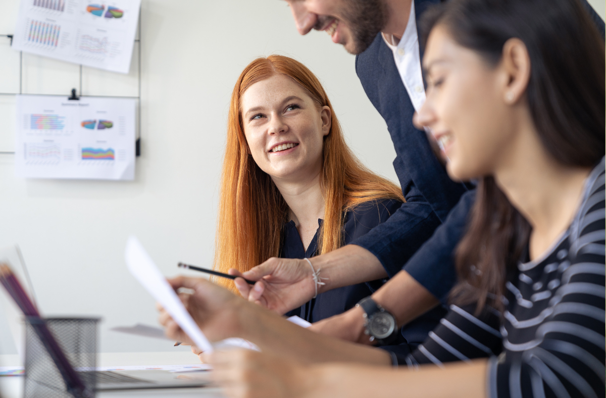 Three people in an office, looking over paperwork.