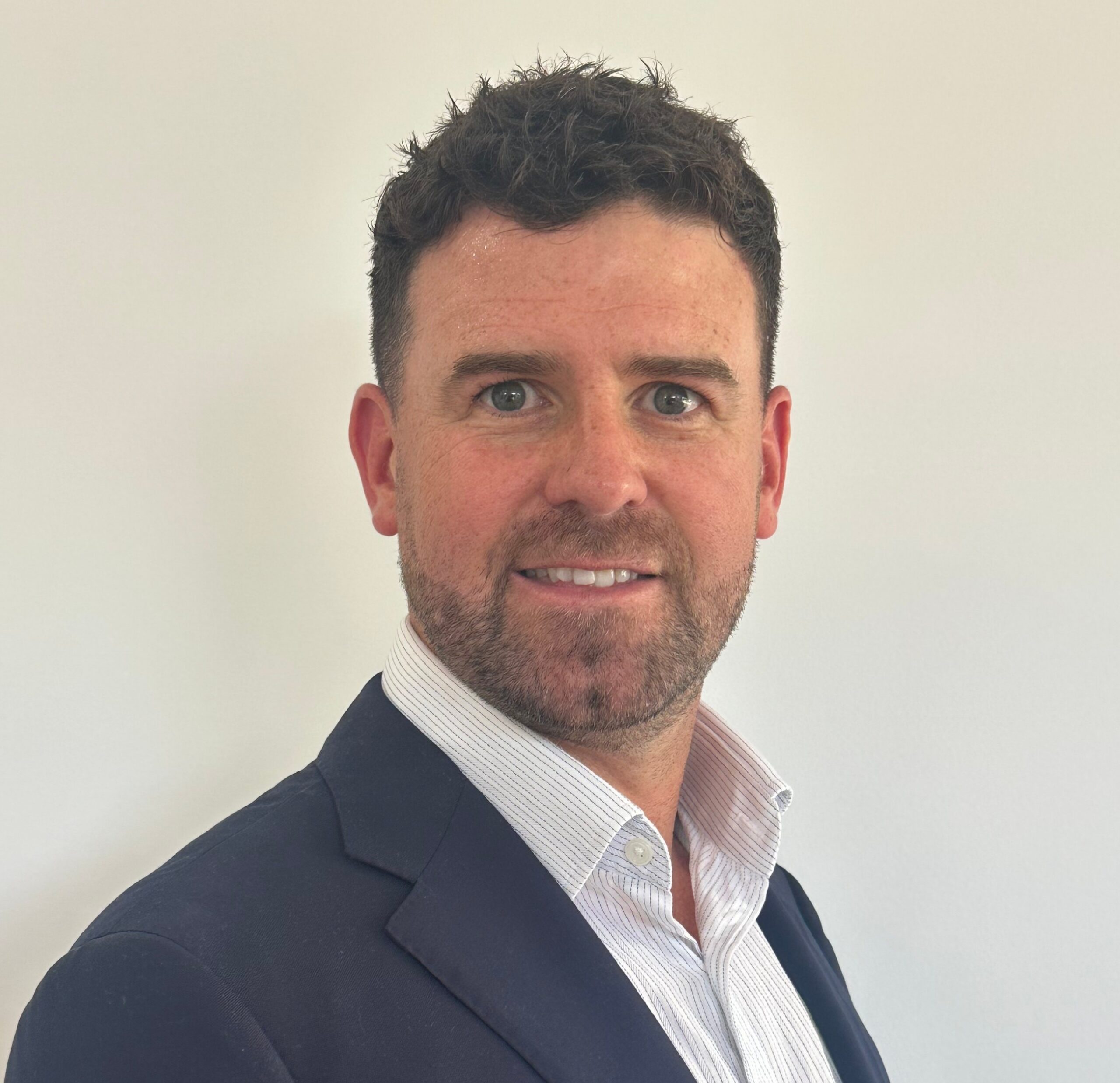 Profile Pic A man with a beard in a navy suit.